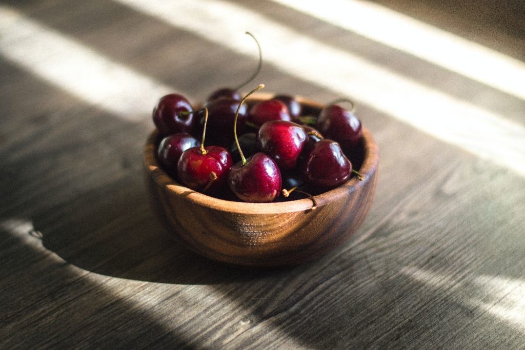 A wooden bowl full of cherries high in antioxidants. 