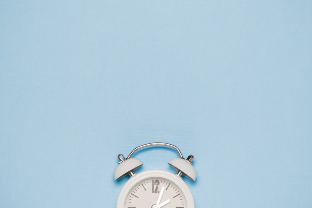 Image of clock against light blue background to represent how timing the intake of carbs can benefit exercise performance