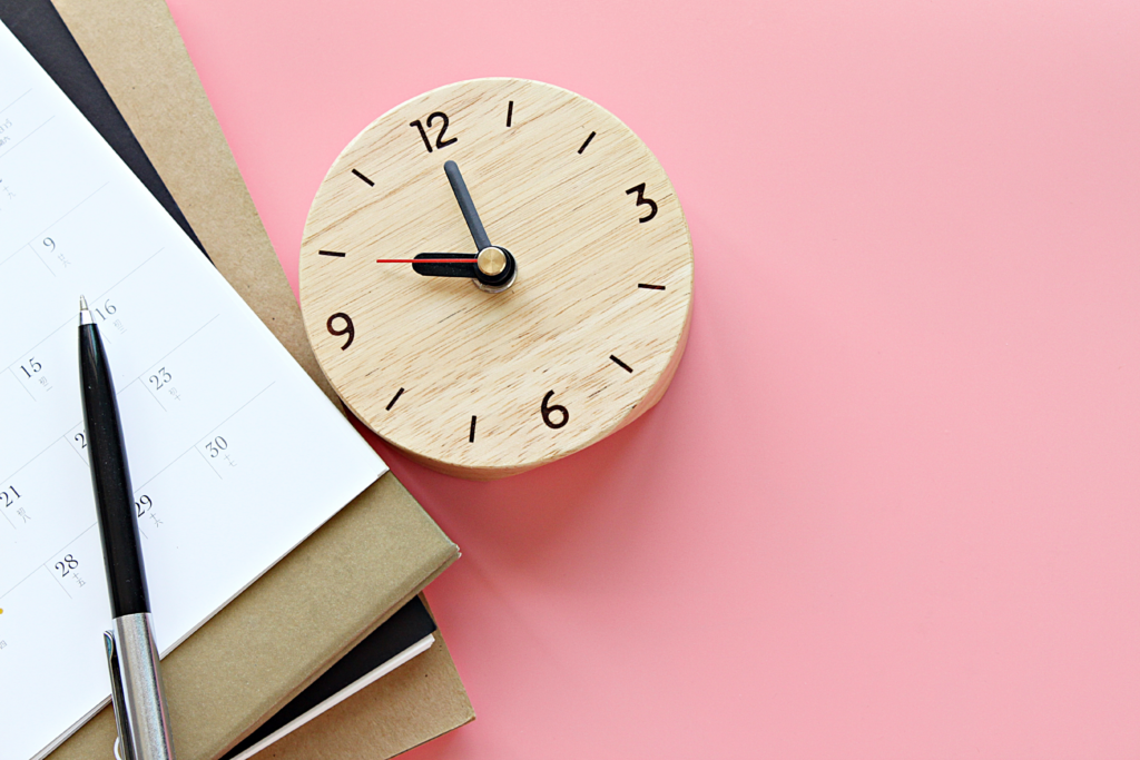 schedule or planner, clock, and pen on a pink background