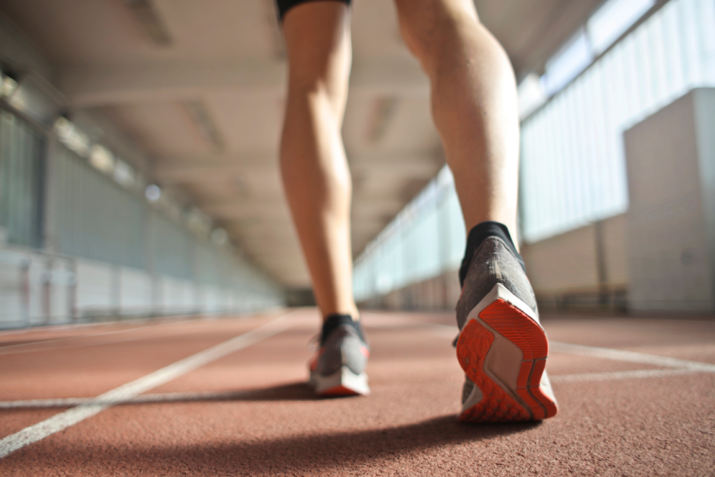 image of runners legs and shoes running on an indoor running track