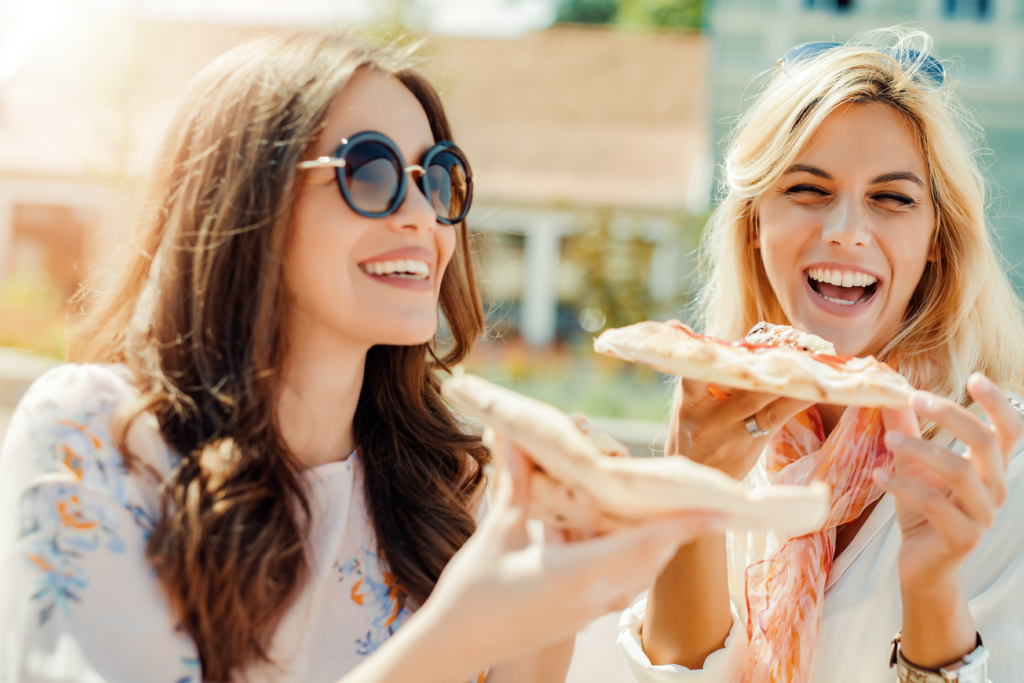 Image of two girls eating pizza together without food guilt.
