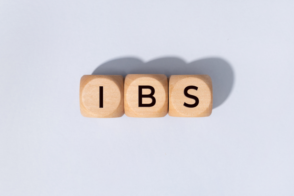 Three wooden blocks with rounded edges lined up beside one another on a white background. The blocks each have a letter and spell IBS for irritable bowel syndrome.
