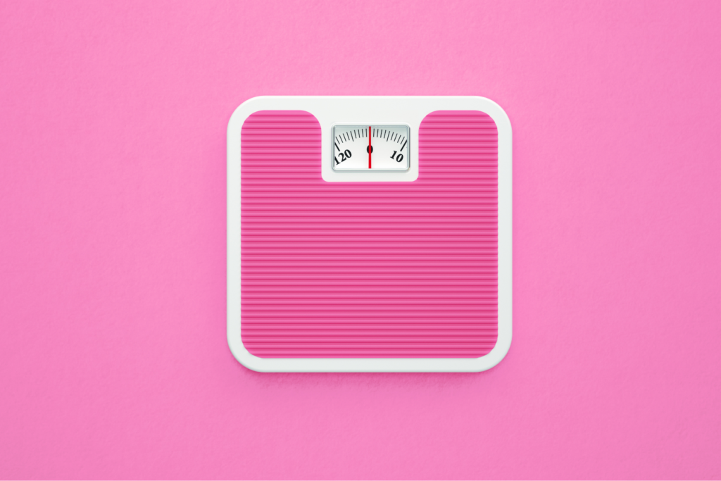 Image of a pink bathroom scale on a pink background. The scale reads zero.