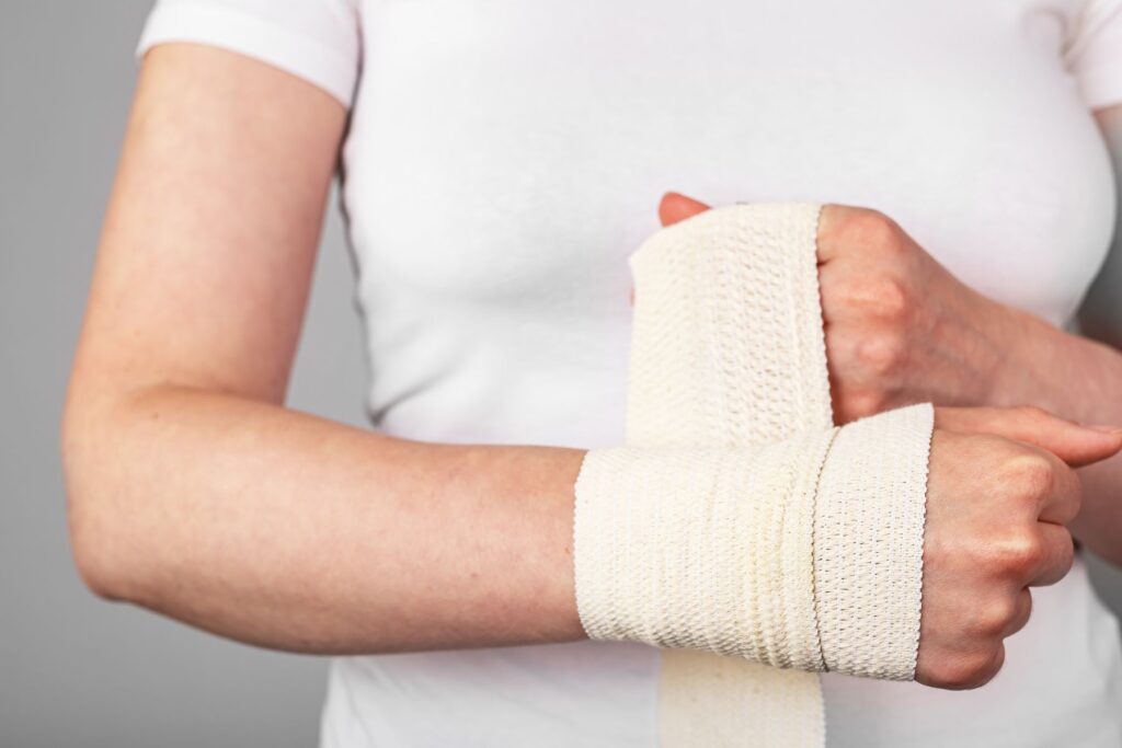 Image of woman in white shirt wrapping her wrist with a white tensor band 
