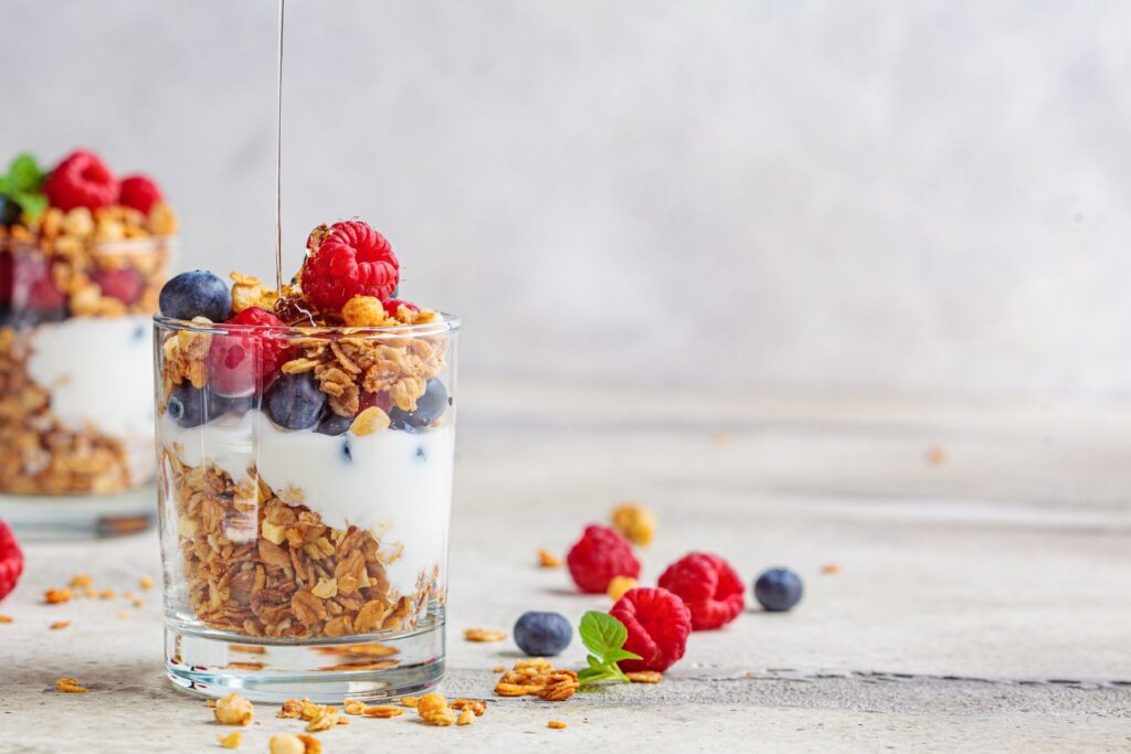 Image of yogurt parfait in clear glass with berries and granola. 