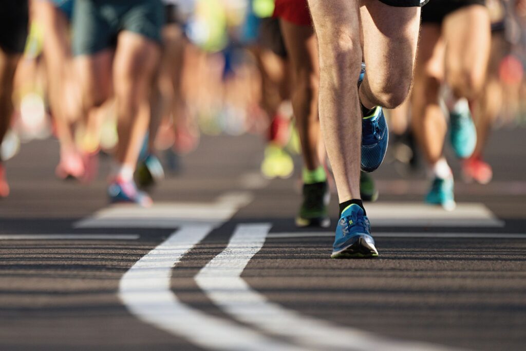 Image of the feet of many runners on pavement as they participate in the challenges of running a marathon 