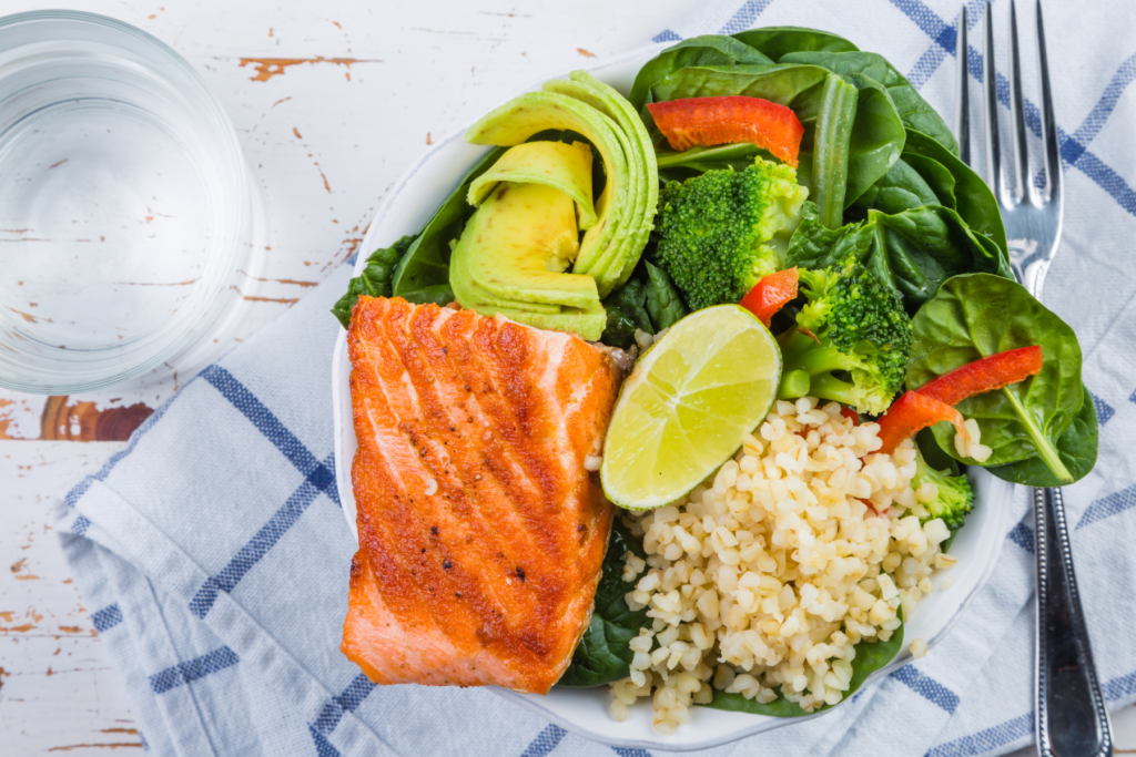 Balanced meal with veg, salmon, rice in a bowl with a glass of water on the side