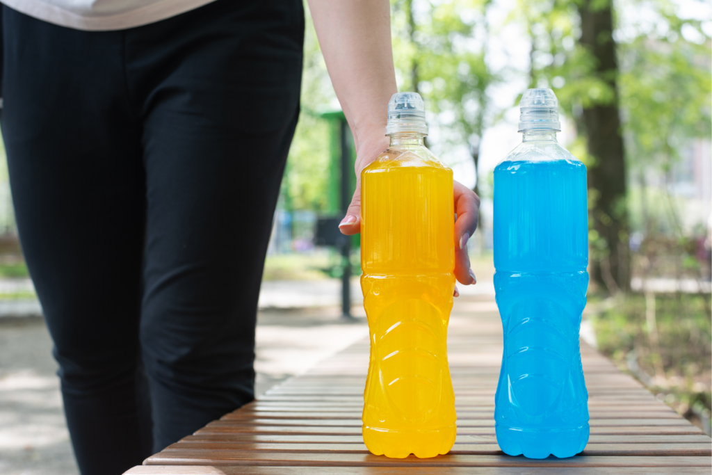 Woman picking up hydration electrolyte drink from a bench outside 