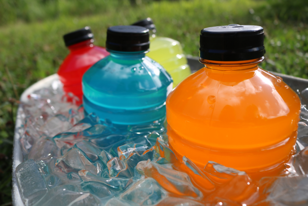 Sports hydration drinks with electrolytes in bucket of ice outside in grass