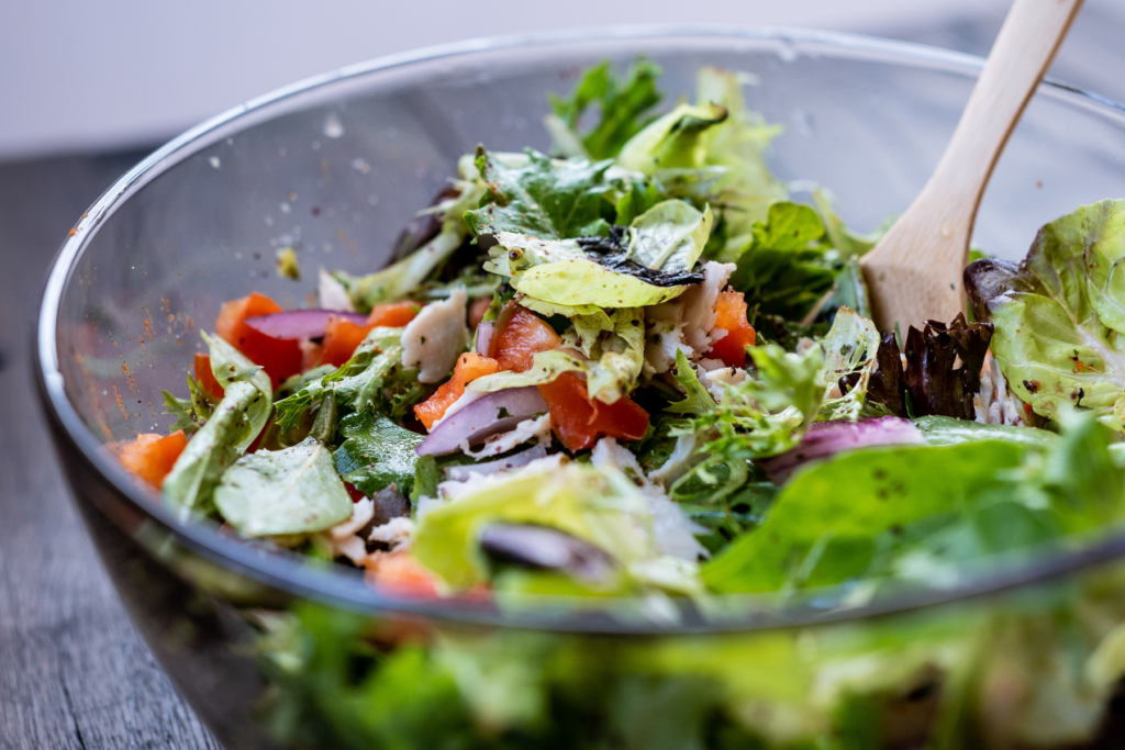 Salad in glass bowl with wooden fork 