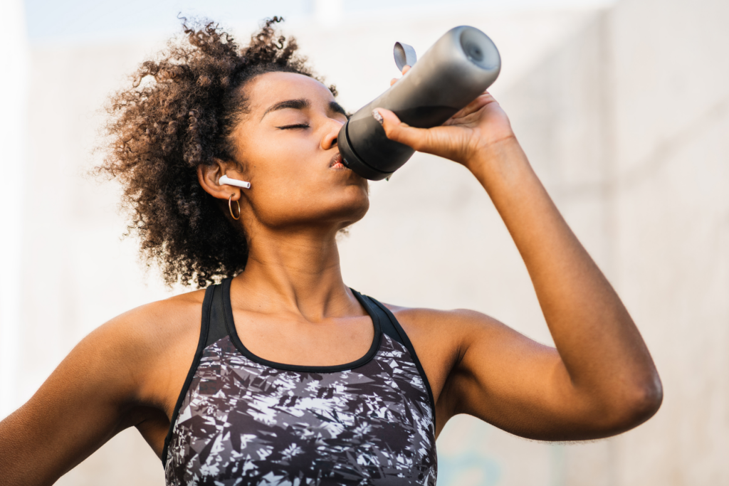 Woman drinking water from water bottle for hydration during exercise 