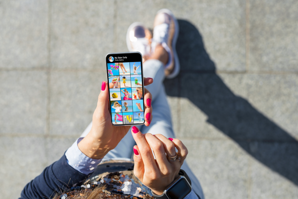 A girl looks down at her smart phone on which the screen displays image son a social media app.